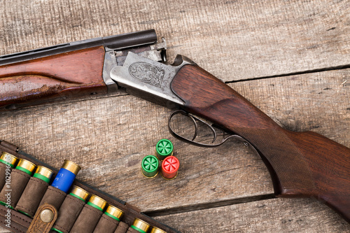 Hunting shotgun and ammunition on wooden background photo