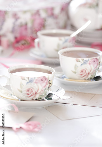 Three cups of tea on a white background. Tea in a bright cups with roses. Vintage style. Bright hues.