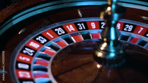Russian roulette wheel is spinning with the small white ball is going around at the game table at casino. 
