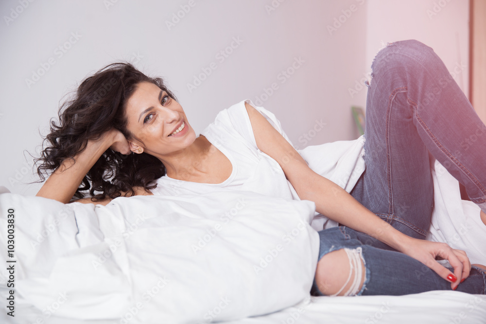 Long hair woman in blue jeans on white bed Long hair woman in blue jeans on white bed