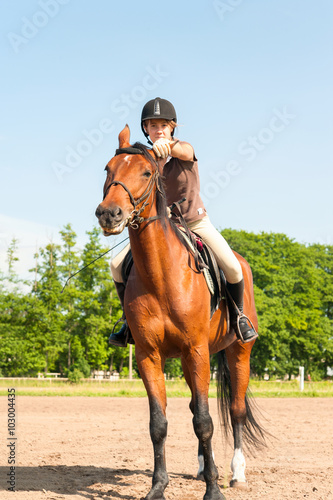 Young teenage girl equestrian riding horseback on chestnut horse