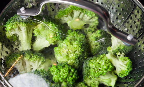 Fototapeta Naklejka Na Ścianę i Meble -  Freshly steamed green broccoli in skimmer pot