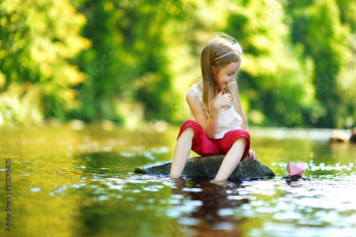 Cute little girl playing with paper boat