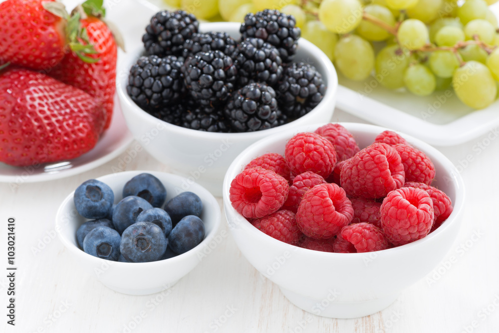 Fresh garden berries and grapes on a white wooden table Fresh garden berries and grapes on a white wooden table