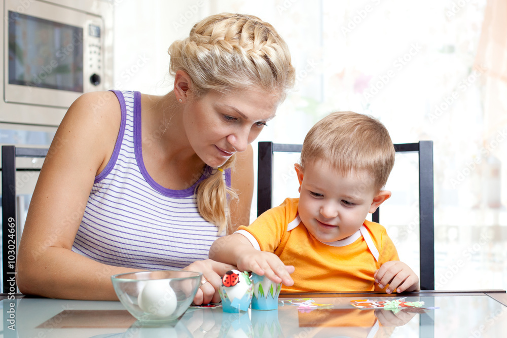 Little toddler boy and his mother having fun with preparing eggs for Easter egg hunt, traditional action for Eastern holiday, at home Little toddler boy and his mother having fun with preparing eggs for Easter egg hunt, traditional action for Eastern holiday, at home