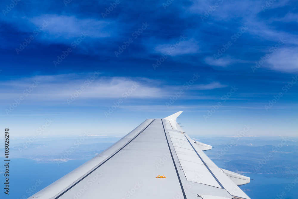 Blue horizon with soft clouds, aerial shot from airplane, with wing visible