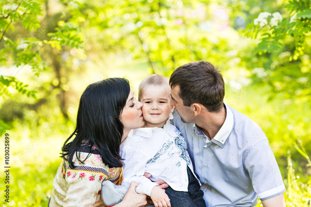 happy mother and father kissing his little son  in park