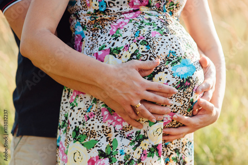 man with pregnant woman hugging and stroking belly