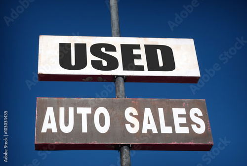 aged and worn vintage photo of used cars sign