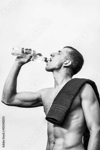 Muscular young man after a workout drinking bottle of water
