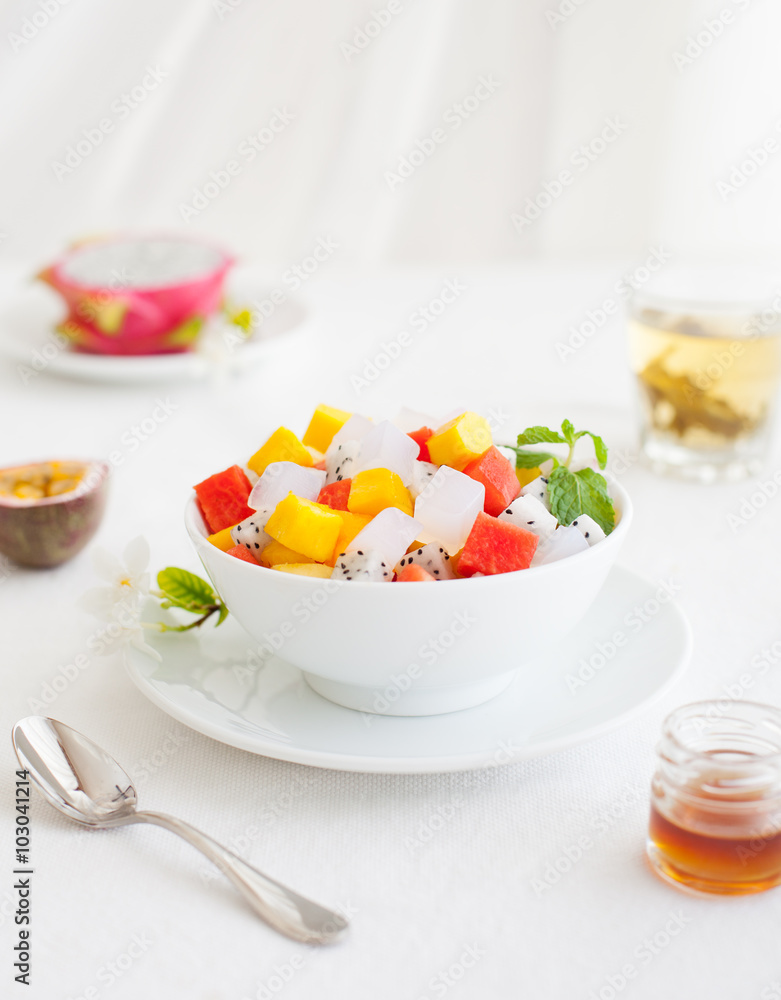 Bowl of fresh exotic fruit salad on white summer background Healthy breakfast