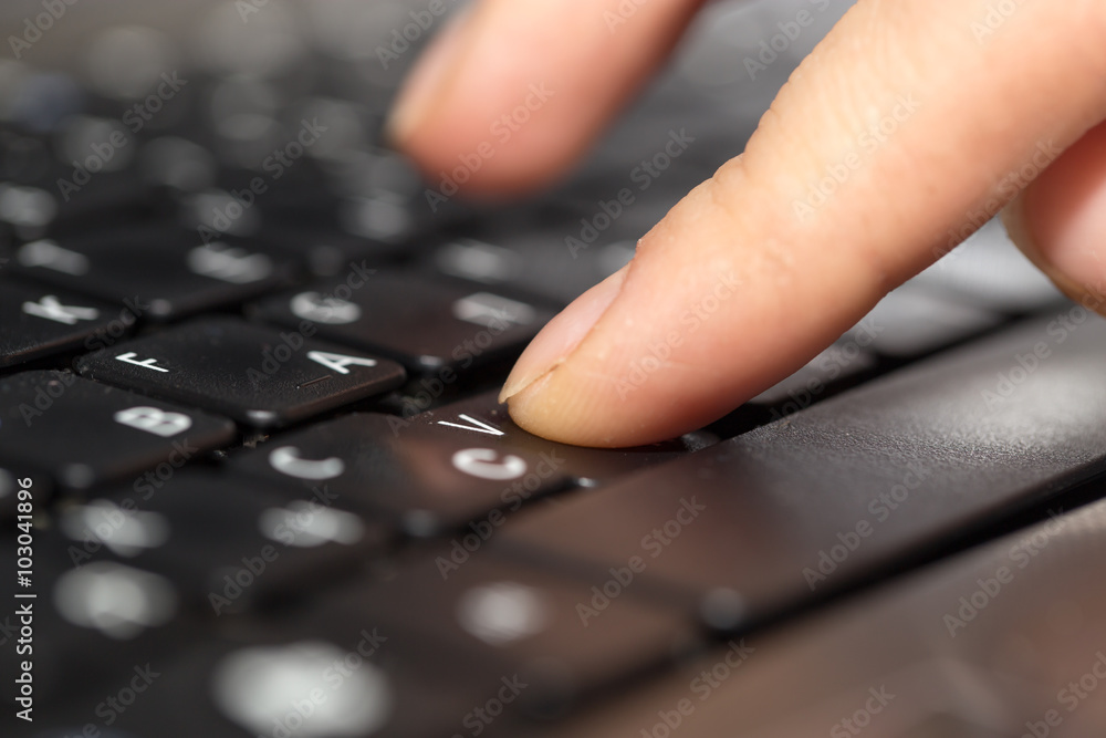 finger on a laptop keyboard finger on a laptop keyboard