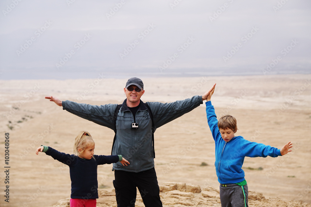 father hiking with two kids in the desert father hiking with two kids in the desert