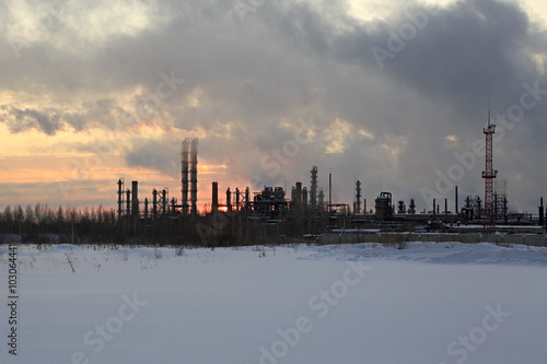 Refinery at sunset sky background. Frosty snowy winter evening.