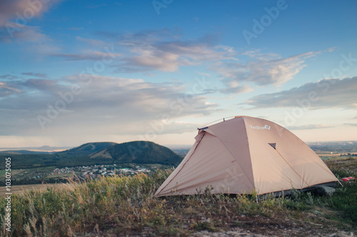 Camping tent in the countryside. Summer, blue sky, clouds and green hills