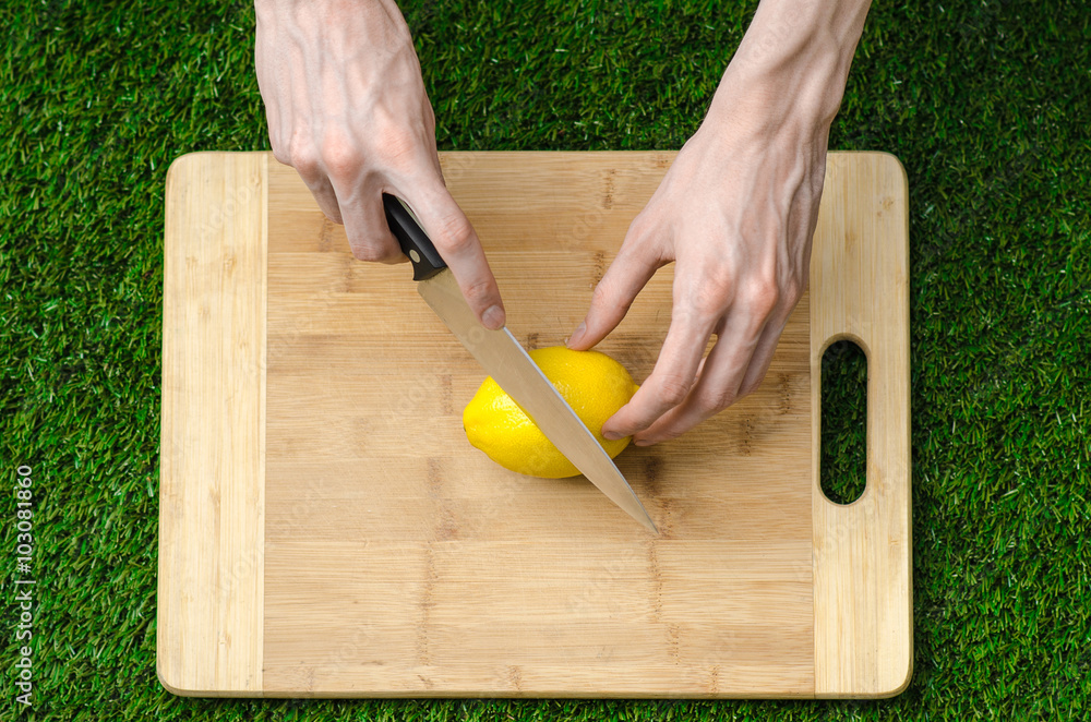 Vegetarians and cooking on the nature of the theme: lying on a cutting board and knife lemon yellow on the background of grass Vegetarians and cooking on the nature of the theme: lying on a cutting board and knife lemon yellow on the background of grass