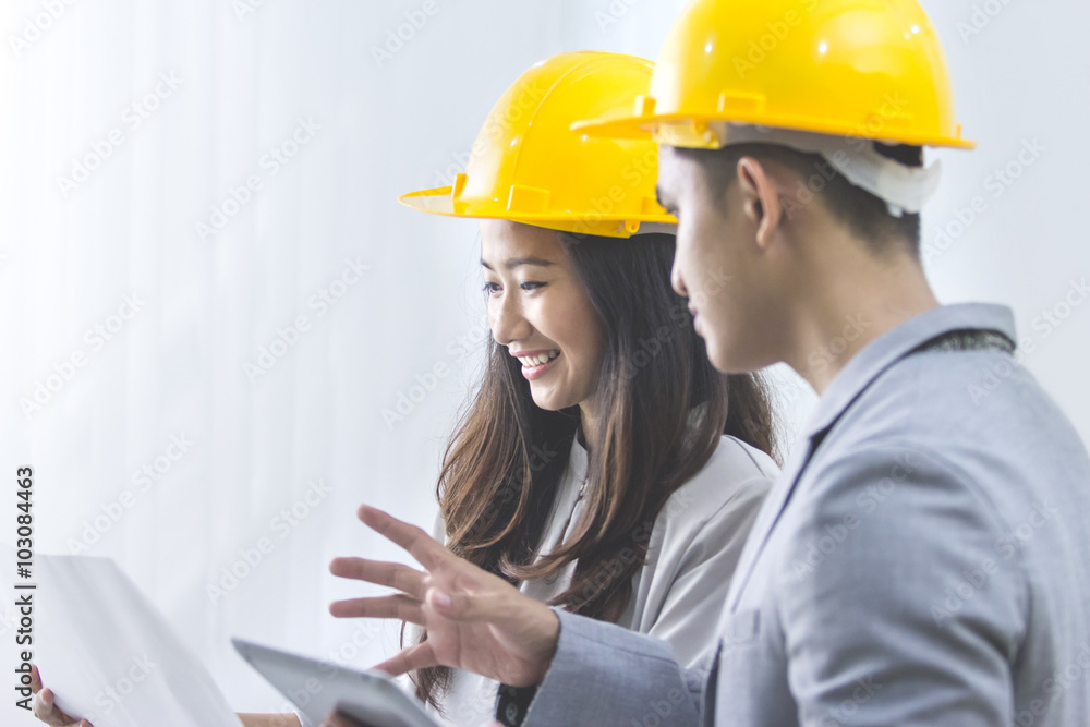 businessman and businesswoman with blueprint and helmets discuss businessman and businesswoman with blueprint and helmets discuss