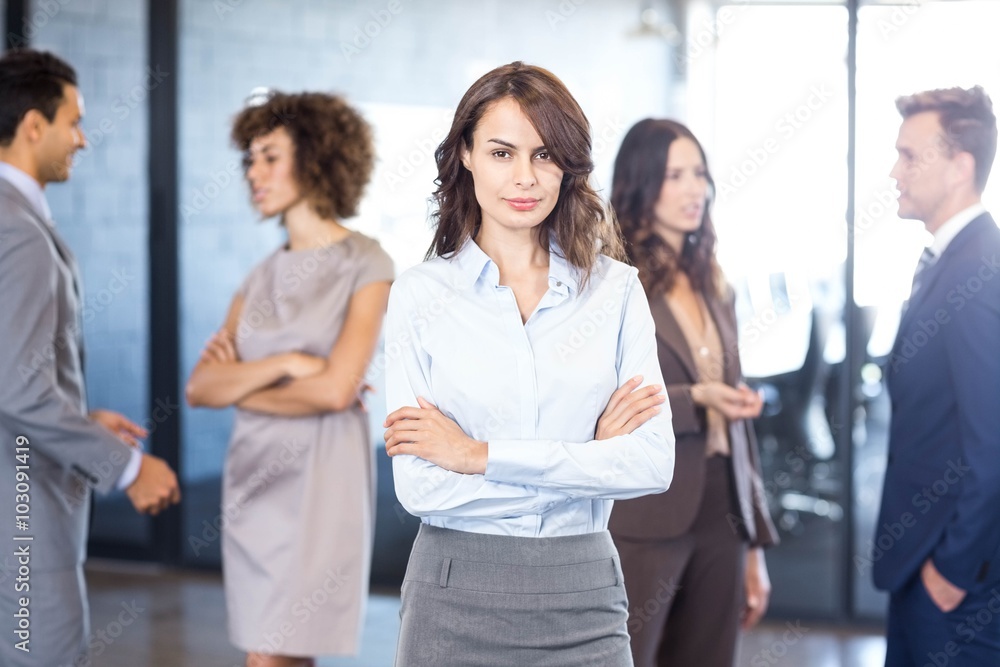 Businesswoman smiling at camera while her colleagues discussing Businesswoman smiling at camera while her colleagues discussing