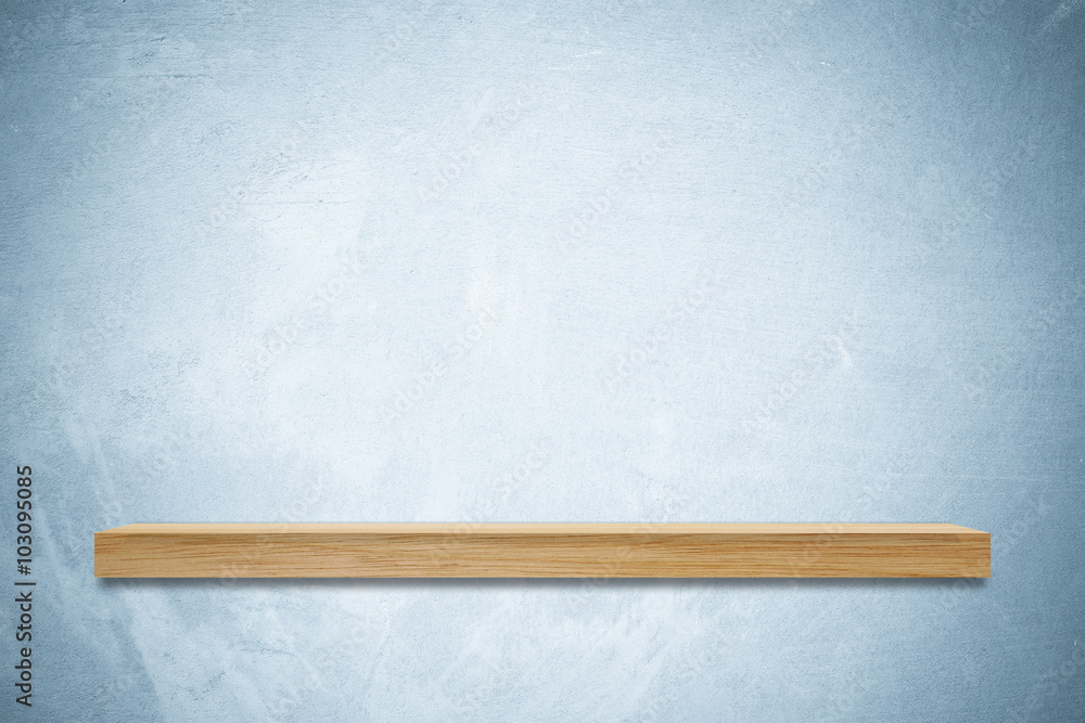 Empty wooden shelf on blue cement wall background