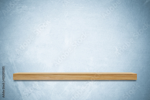 Empty wooden shelf on blue cement wall background
