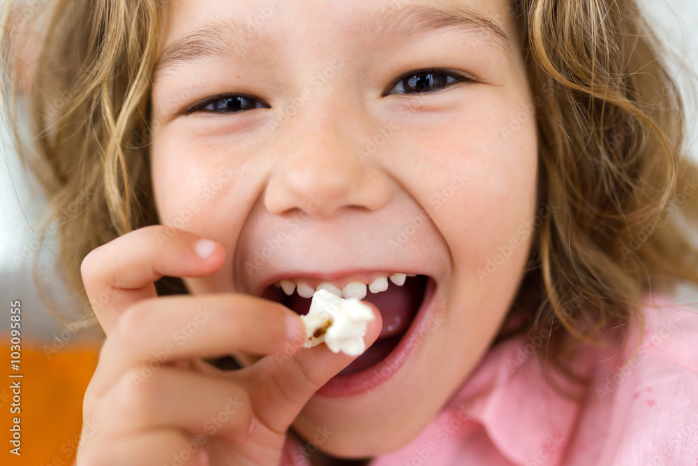 Beautiful young girl eating popcorns at home. Beautiful young girl eating popcorns at home.