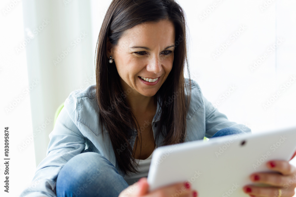 Beautiful young woman using her digital tablet at home. Beautiful young woman using her digital tablet at home.