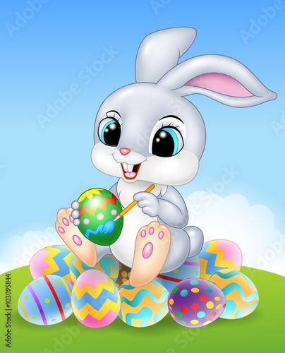 Cartoon Easter Bunny painting an egg on the easter eggs