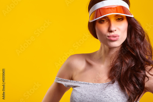 Smiling young woman in orange sun visor posing in sunlight and 