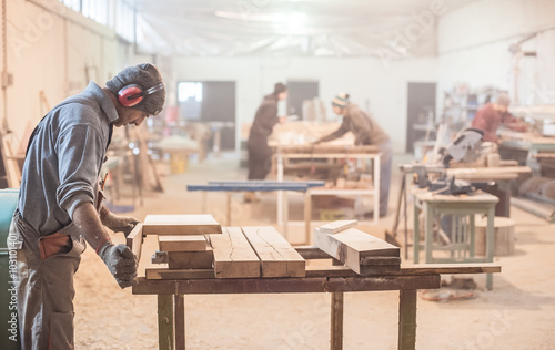 Man doing woodwork in carpentry / Carpenter work on wood plank in workshop photo