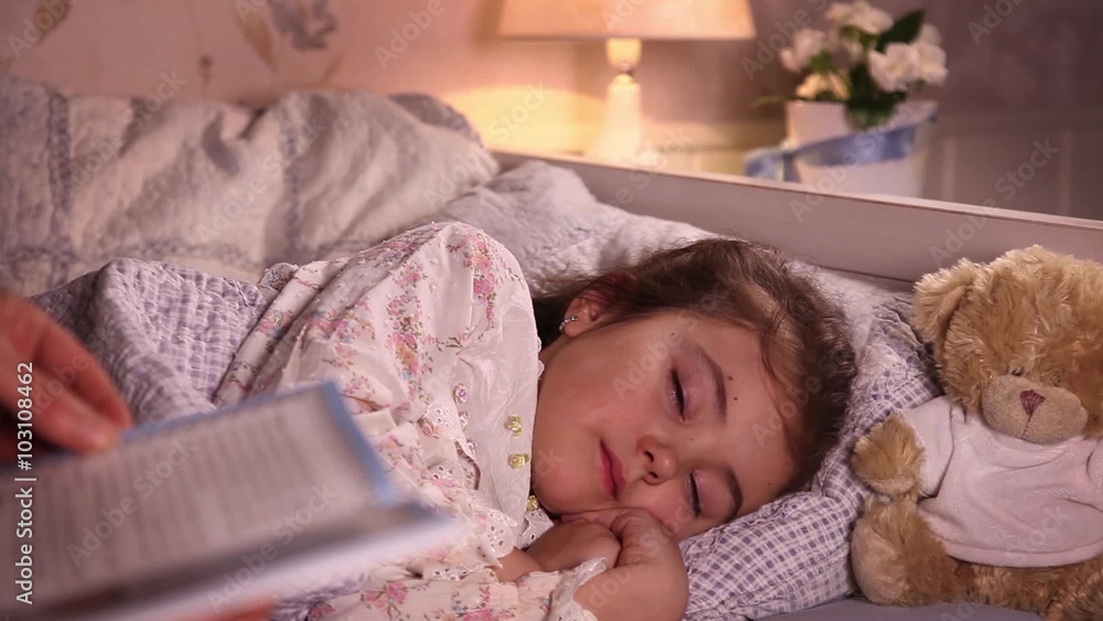 Mom reading a book while putting her little daughter to sleep
Mom reading a book while putting her little daughter to sleep