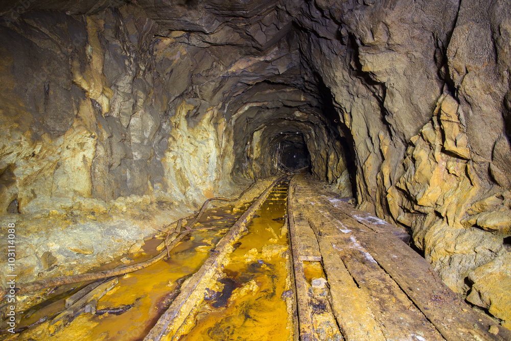 Old abandoned gold mine tunnel passage with rails