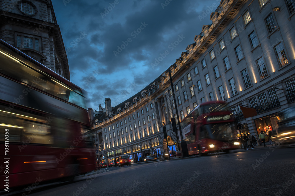 Double decker buses and other traffic on a crowded Regent street, the shopping center of London that connects Oxford Circus to Piccadilly Circus, at night in England, United Kingdom