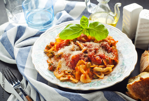 a plate of pasta farfallе with tomato sauce and green peas. hea photo