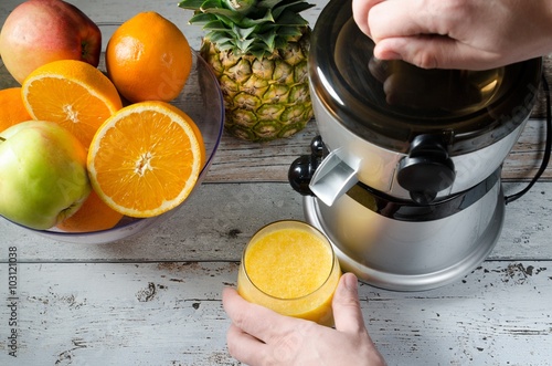 Fotografie Man preparing fresh orange juice. Fruits in background