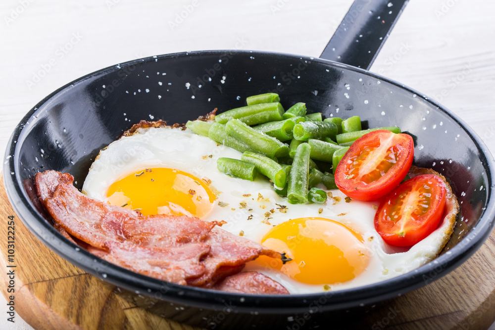 Fried egg on a pan served with tomato and asparagus Fried egg on a pan served with tomato and asparagus