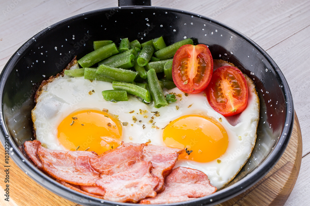 Fried egg on a pan served with tomato and asparagus Fried egg on a pan served with tomato and asparagus