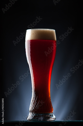 Tall glass of dark beer over a dark background