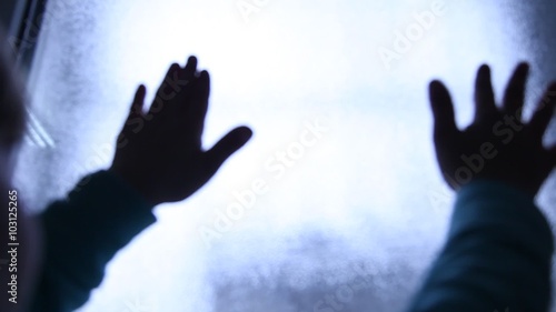 Helpless Child seeking exit and begging for help. Escape. Silhouette of children hands on the light window. Refugees or abandoned child. Mental Institution. Family violence. Fingers on the glass