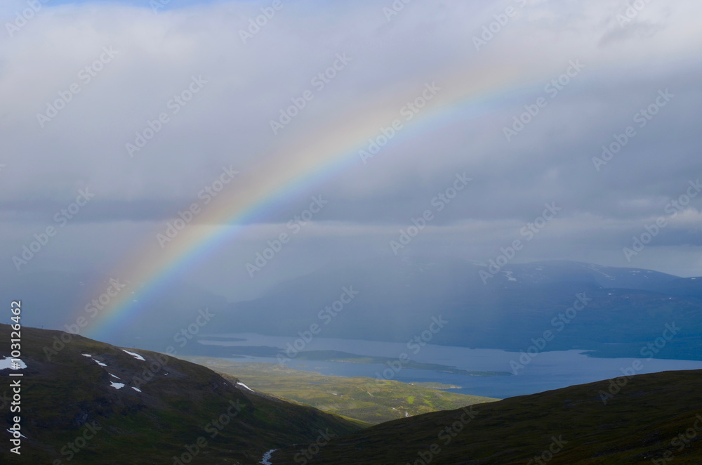 Dark clouds, rainbow and sunshine over tundra and lakes in subarctic mountains, Swedish Lapland