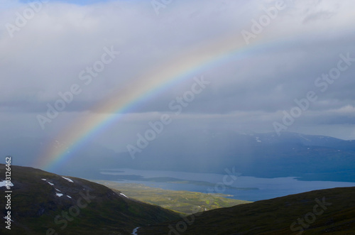 Dark clouds, rainbow and sunshine over tundra and lakes in subarctic mountains, Swedish Lapland