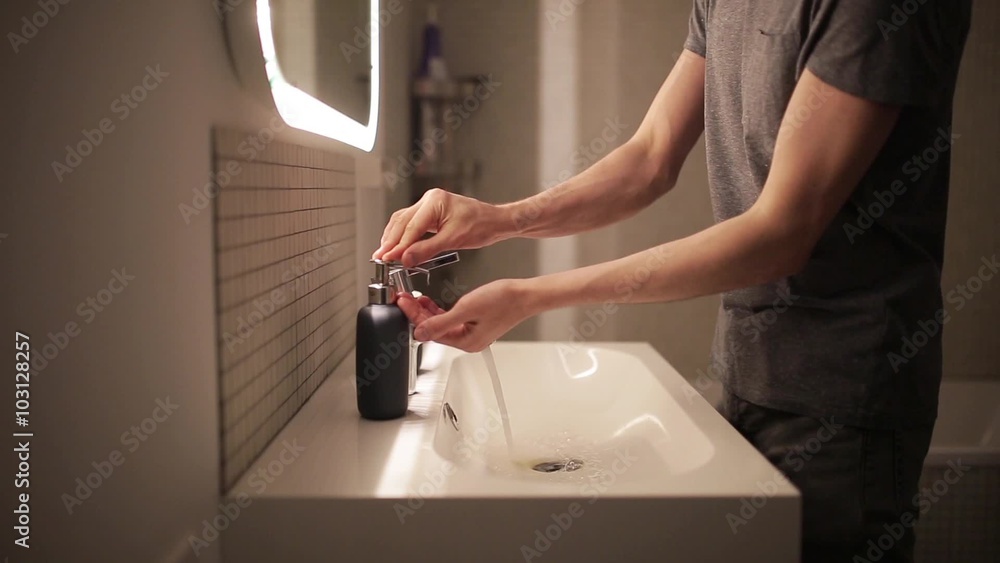 Young man washes his hands in the bathroom Young man washes his hands in the bathroom