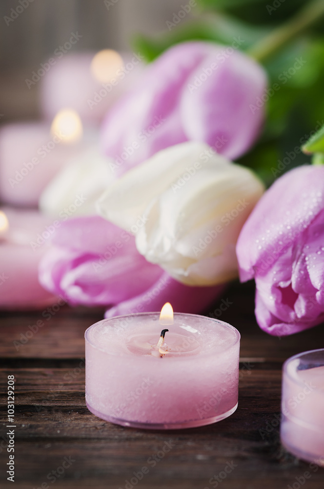 Pink and white tulips and candles on the wooden table