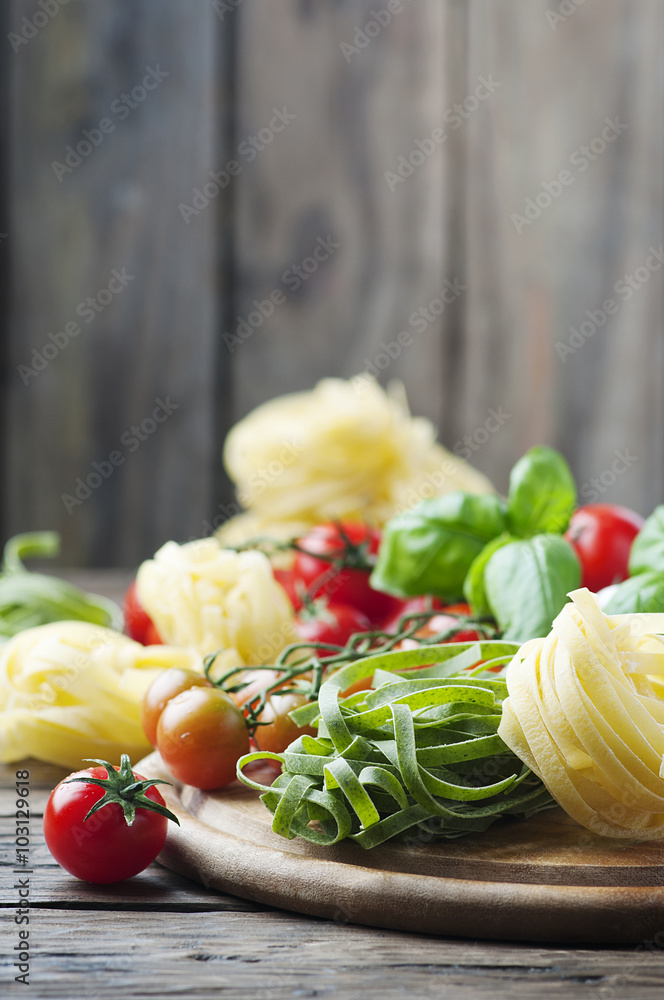 Raw pasta, tomato and basil on the wooden table Raw pasta, tomato and basil on the wooden table