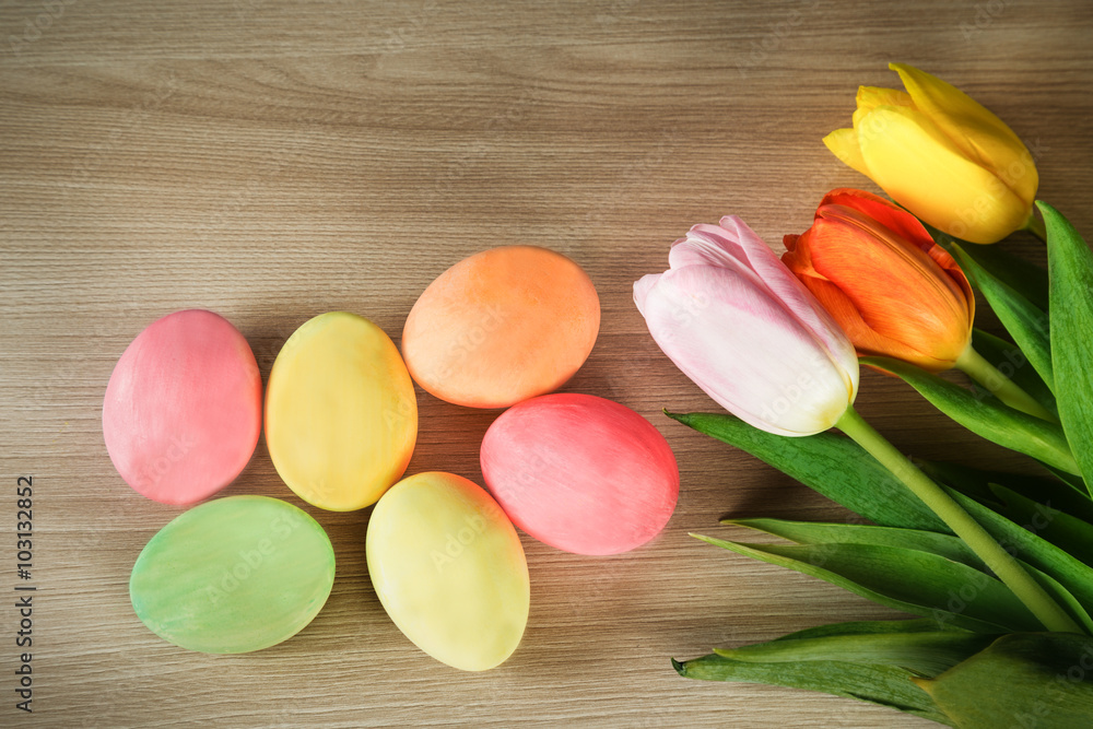 Painted eggs and spring colored tulips on a wooden surface Painted eggs and spring colored tulips on a wooden surface