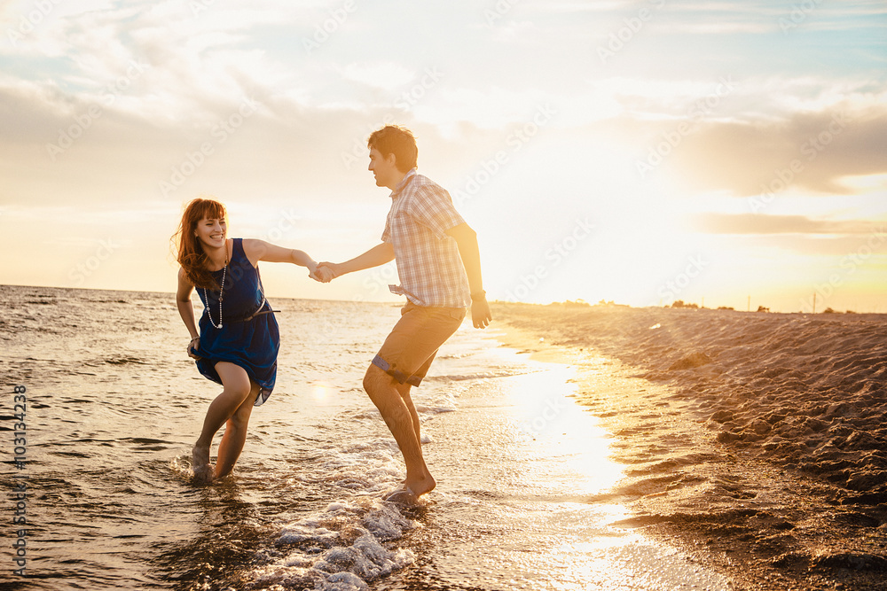 a young couple enjoys a mid summer late afternoon, on a wet san a young couple enjoys a mid summer late afternoon, on a wet san