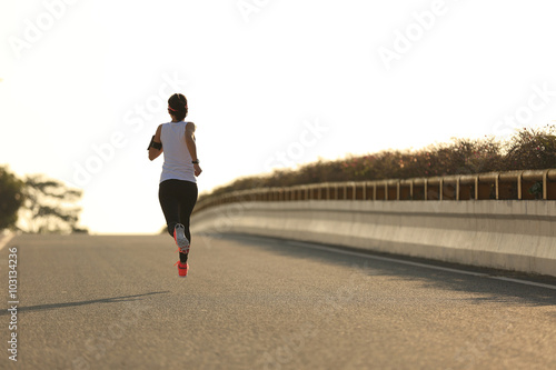 young fitness woman runner running on sunrise road