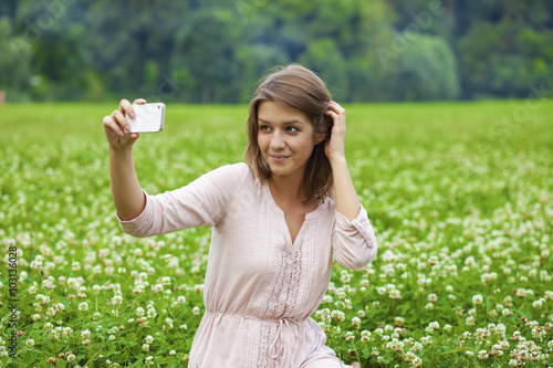 Young beautiful blonde woman photographing themselves on a cell