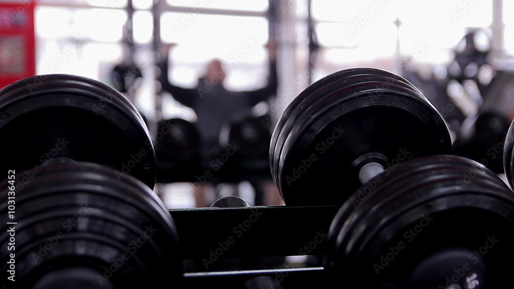 Defocused silhouette of male athlete doing bench press exercise in the gym Defocused silhouette of male athlete doing bench press exercise in the gym