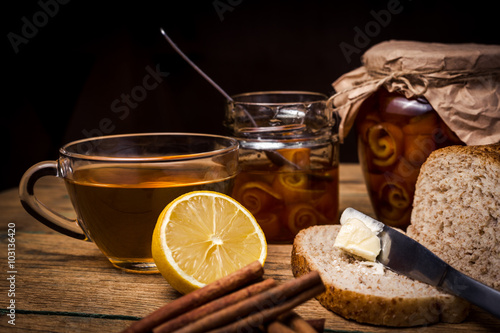 Tea and bread with orange marmalade on wooden background