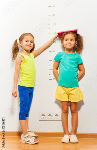 Canvas-taulu Little girl help friend to measure height on scale